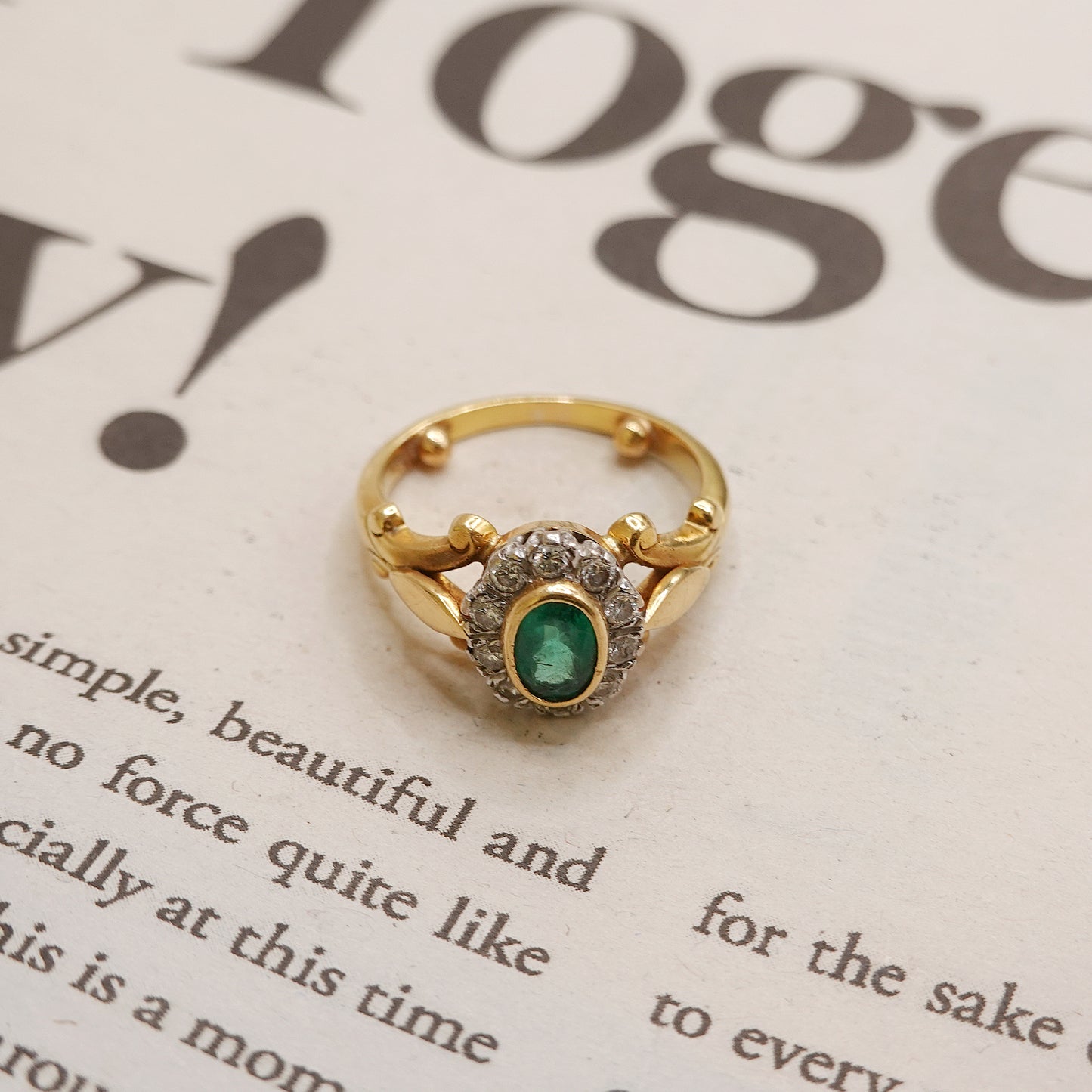 Gold ring with a green emerald gemstone on a newspaper background