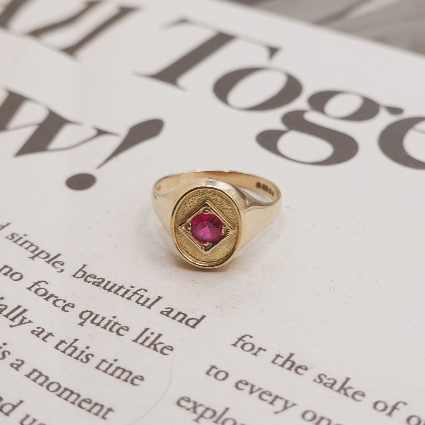 Gold ring with a red gemstone on a newspaper background
