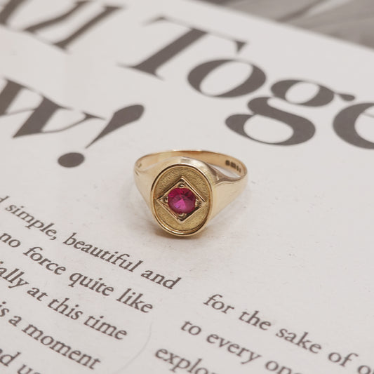 Gold ring with a red gemstone on a newspaper background