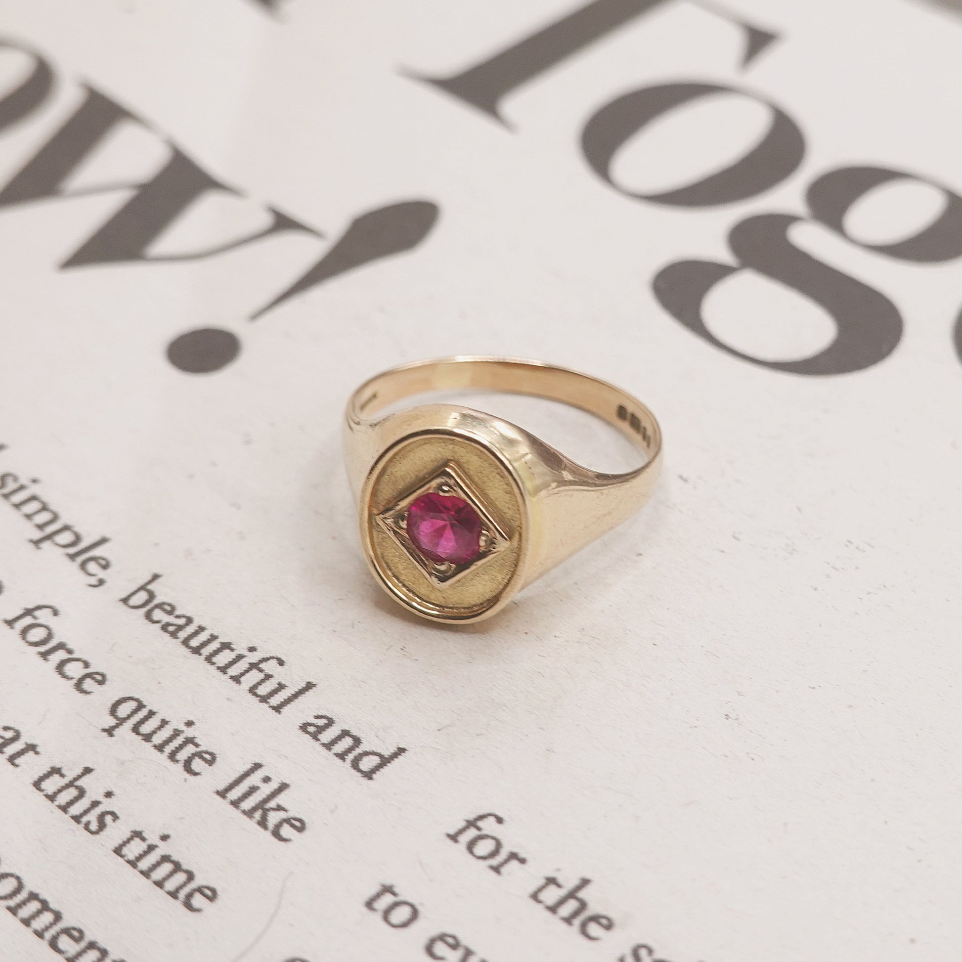 Gold ring with a red gemstone on a newspaper background