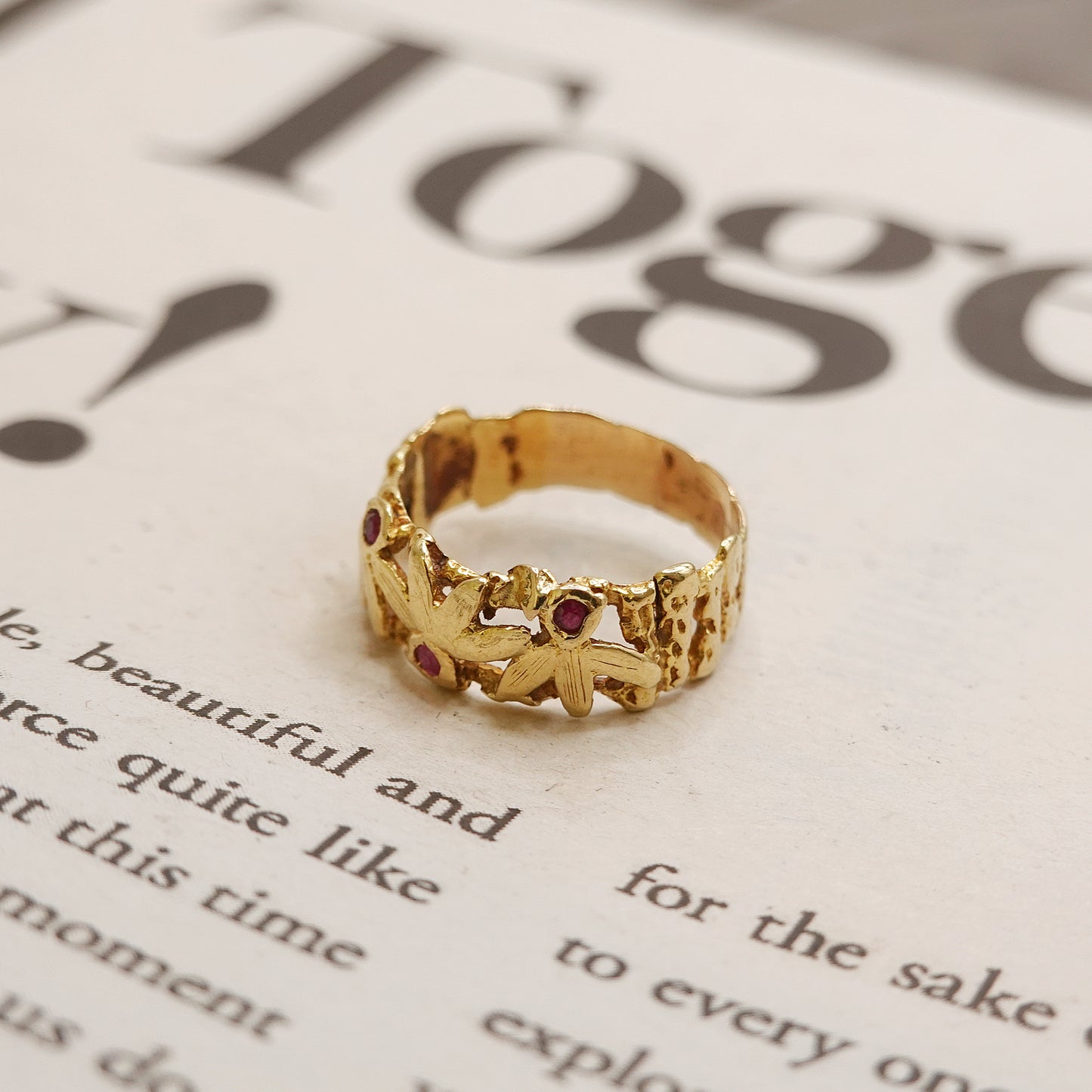 Gold ring with red ruby stones on a piece of paper