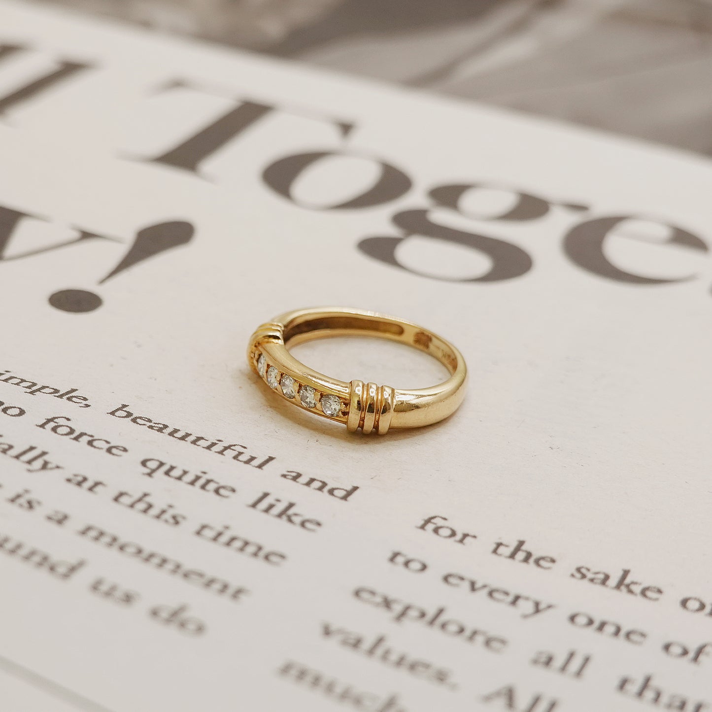 Gold ring with small diamonds on a magazine page