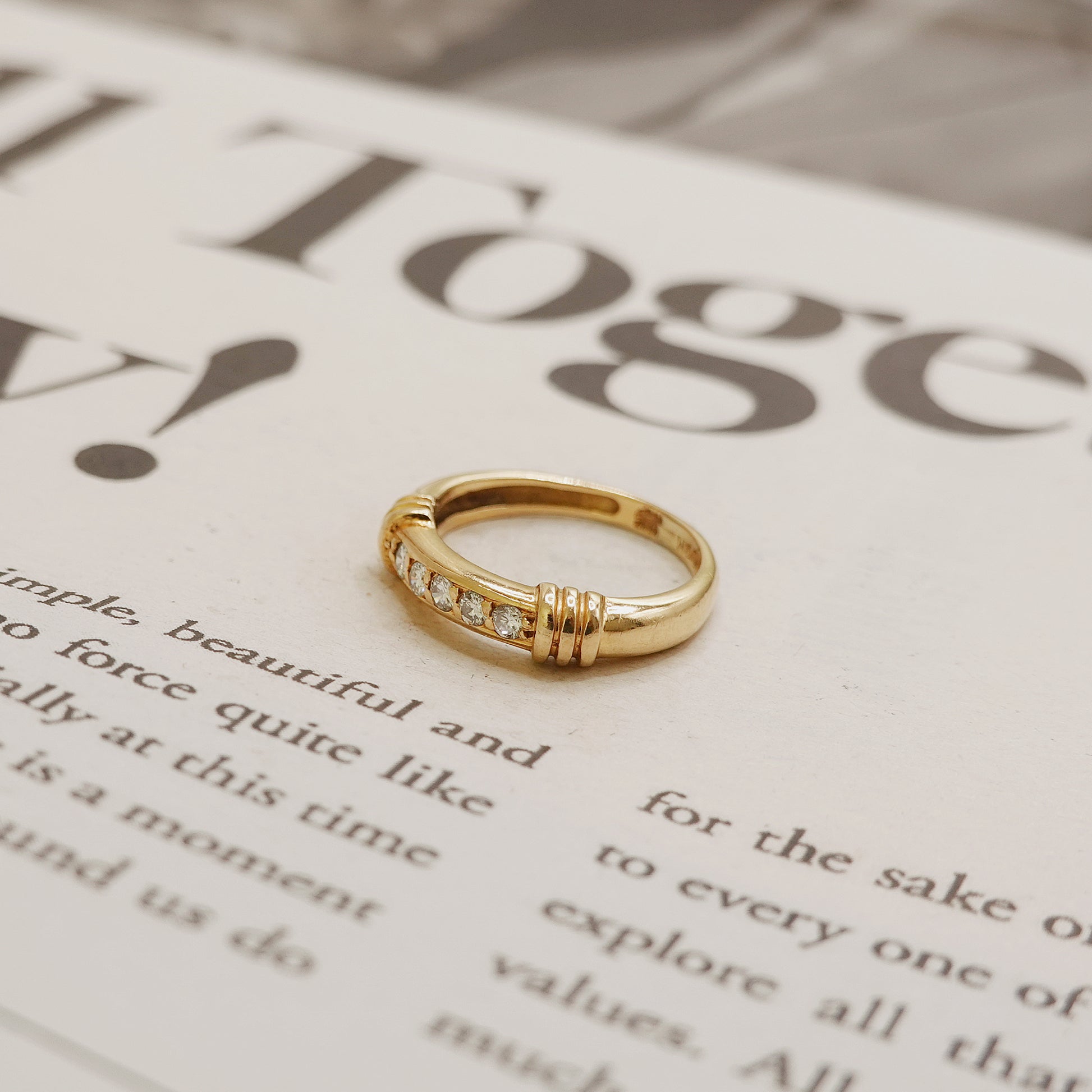 Gold ring with small diamonds on a magazine page