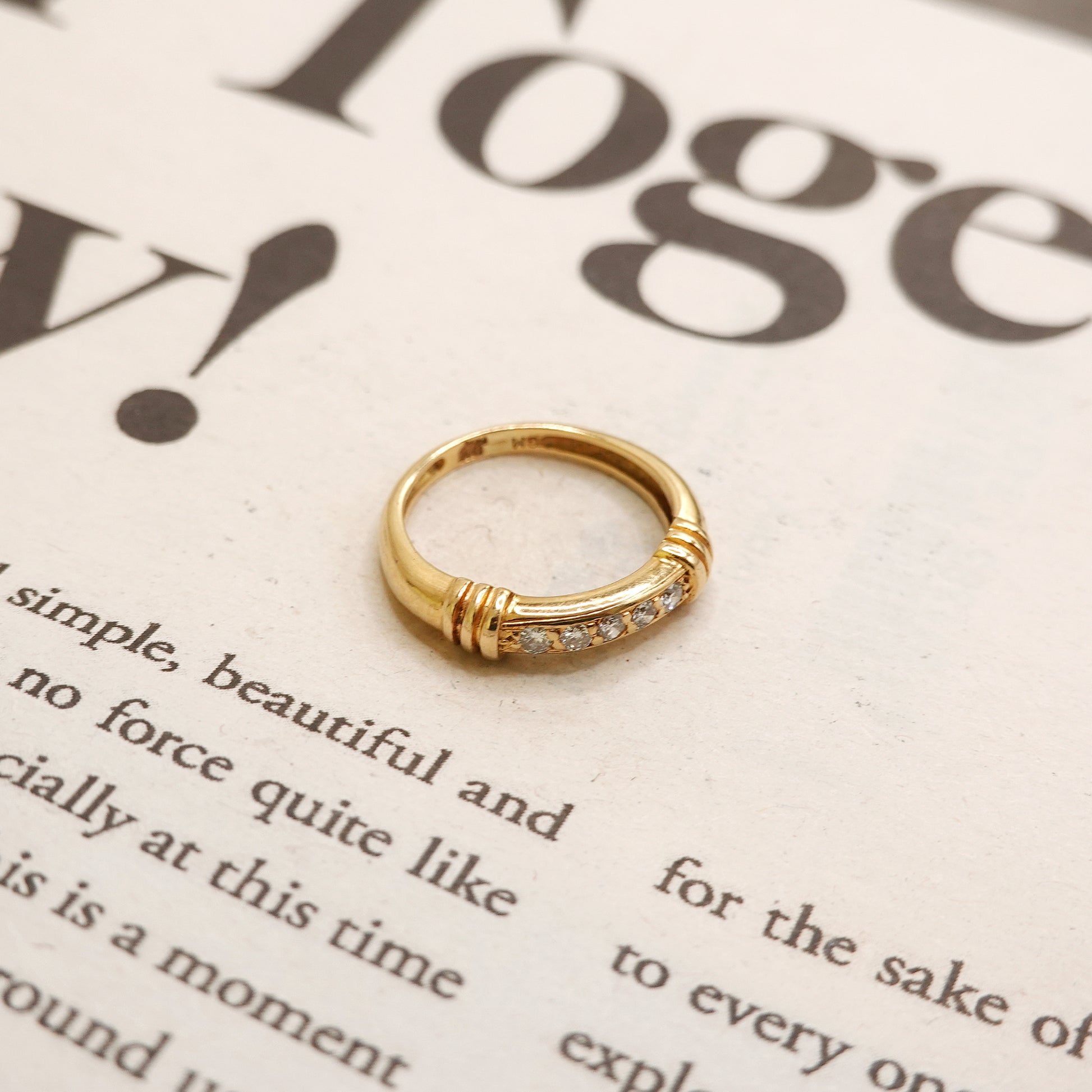 Gold ring with small diamonds on a newspaper background