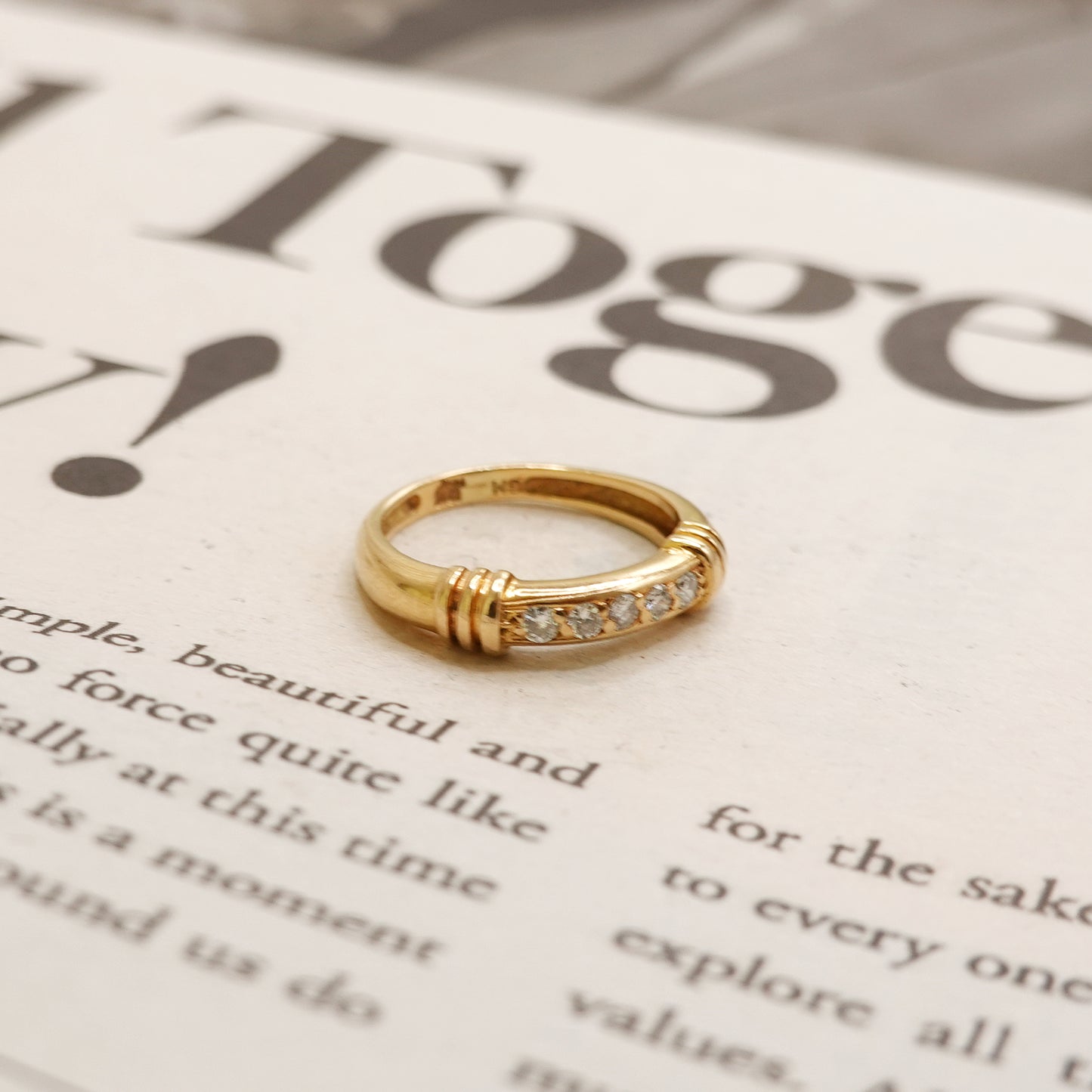 Gold ring with small diamonds on a newspaper background