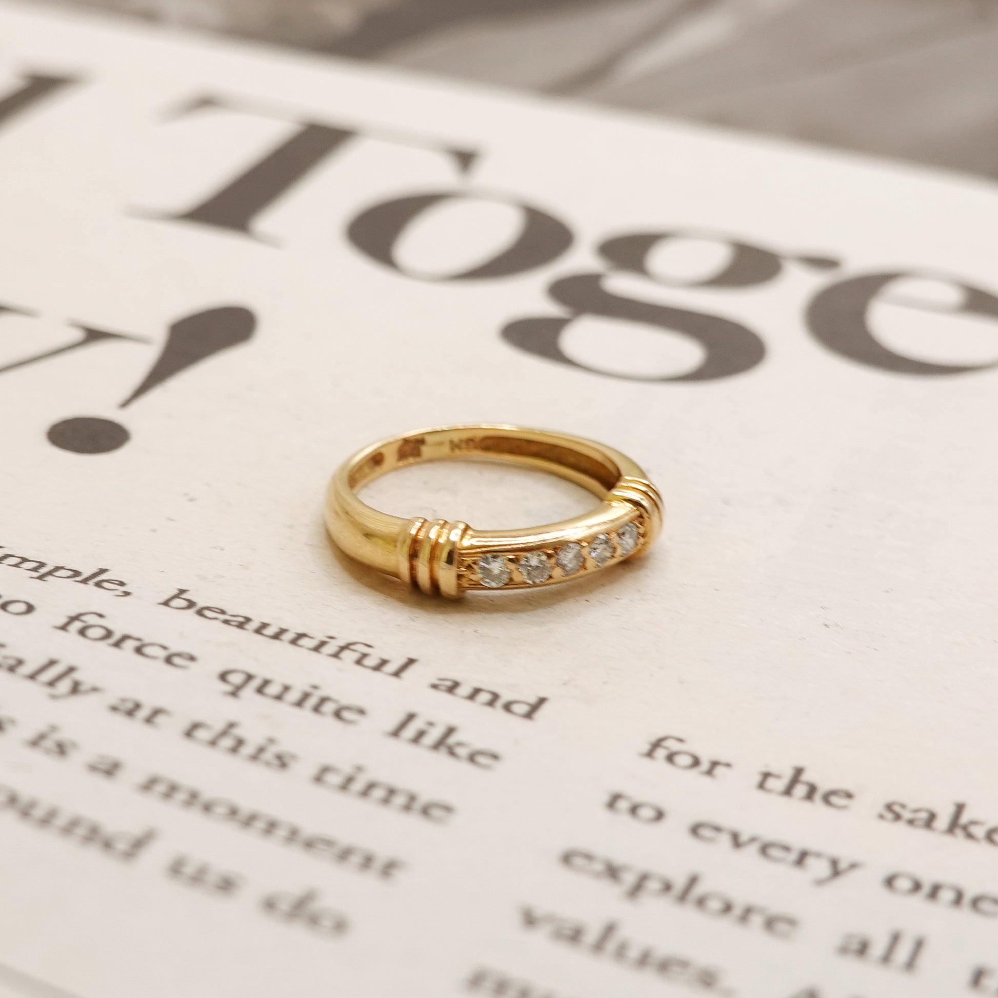 Gold ring with small diamonds on a newspaper background