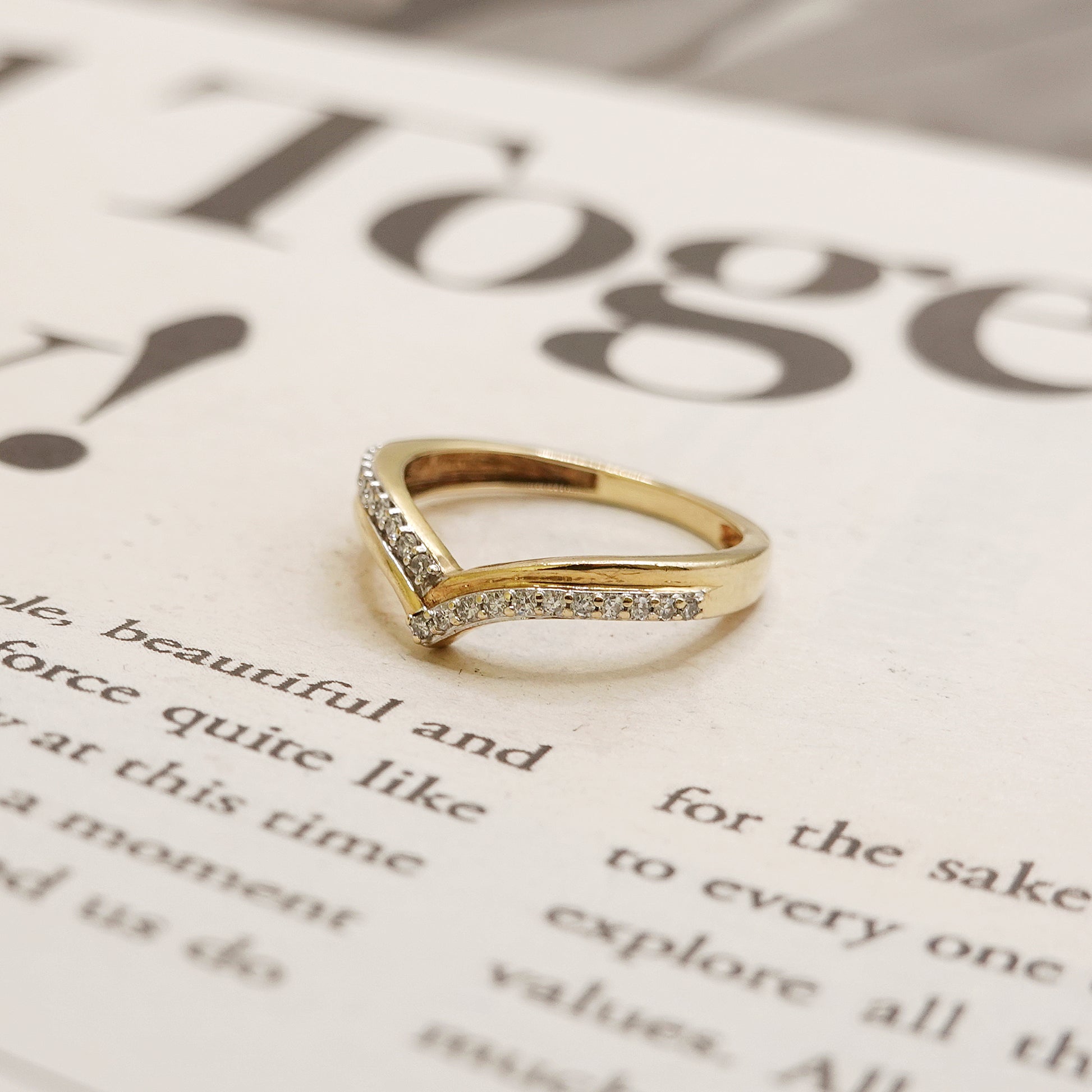Gold ring with diamond accents on a newspaper background