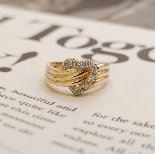 Gold heart-shaped ring with diamonds on a newspaper background