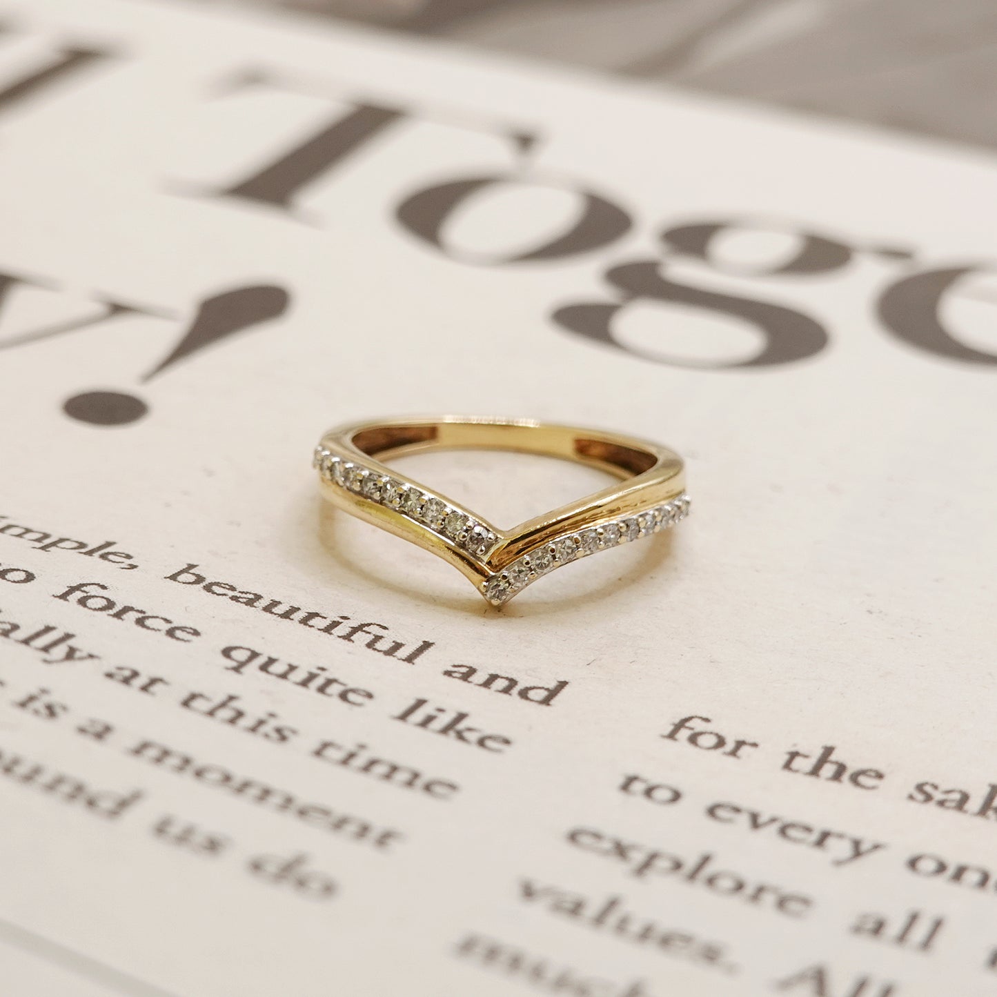 Gold ring with diamond accents on a newspaper background