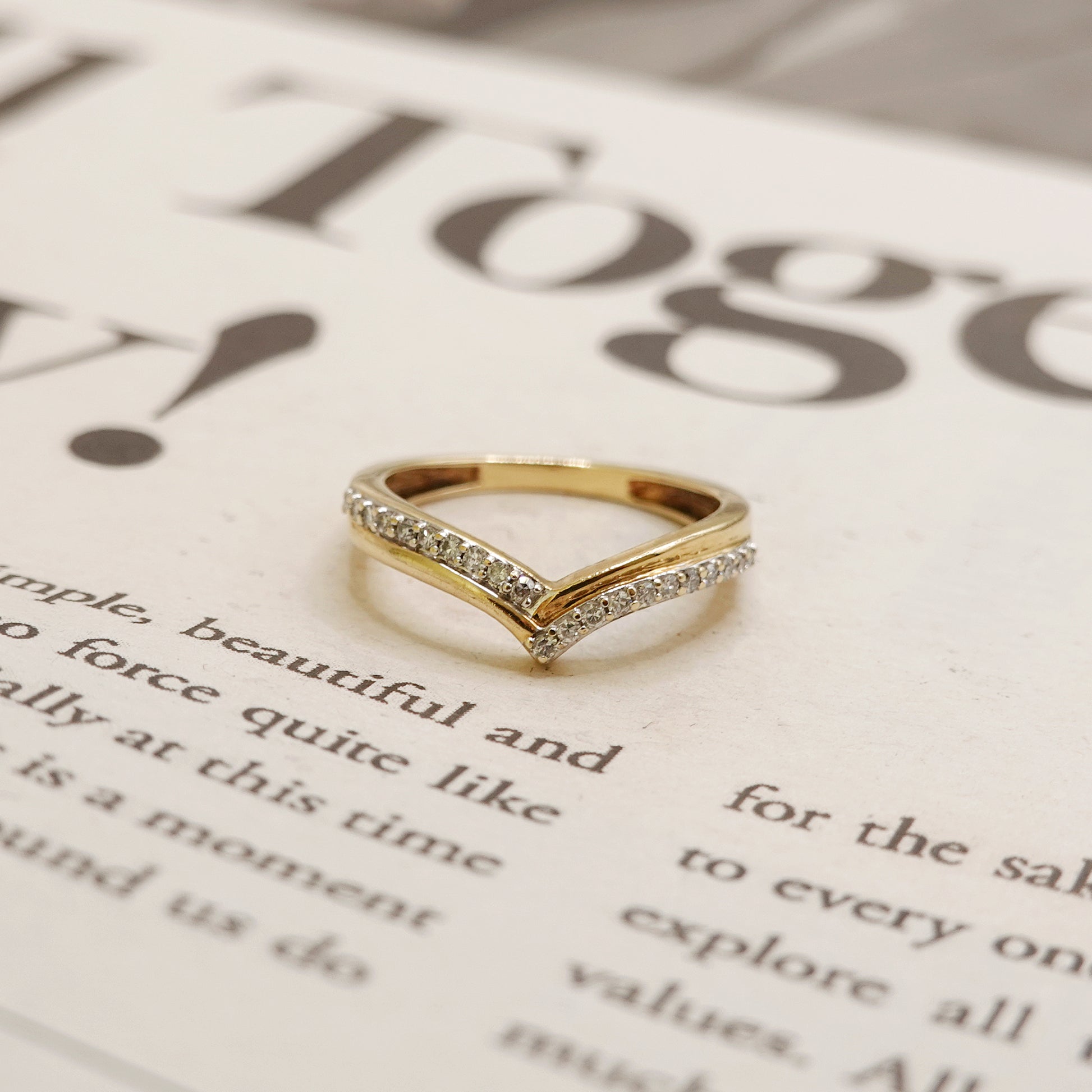 Gold ring with diamond accents on a newspaper background