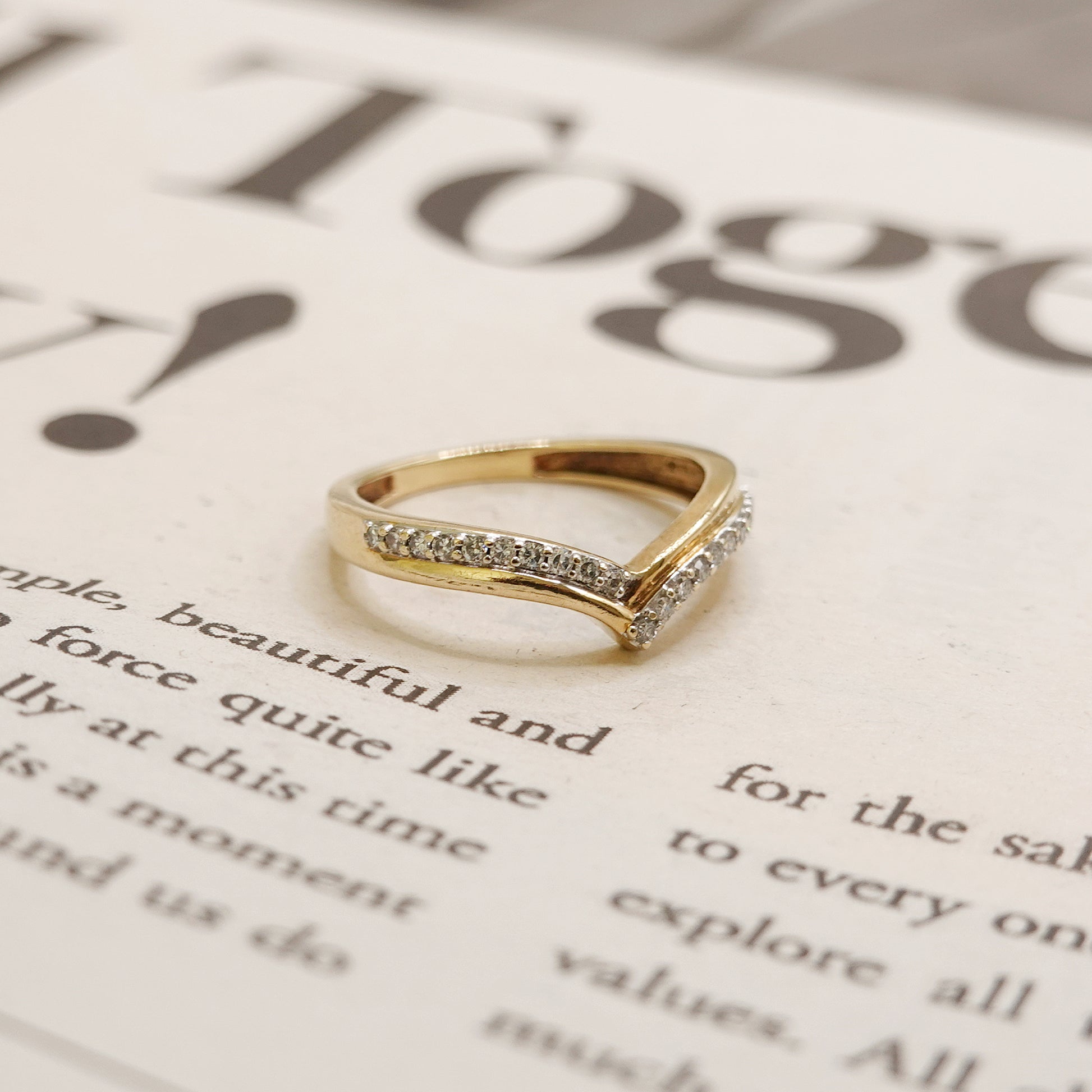 Gold ring with diamonds on a printed paper background
