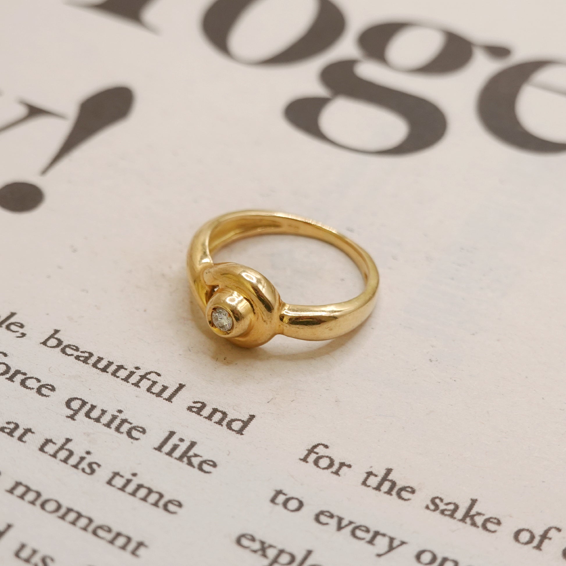 Gold ring with a diamond on a piece of text paper