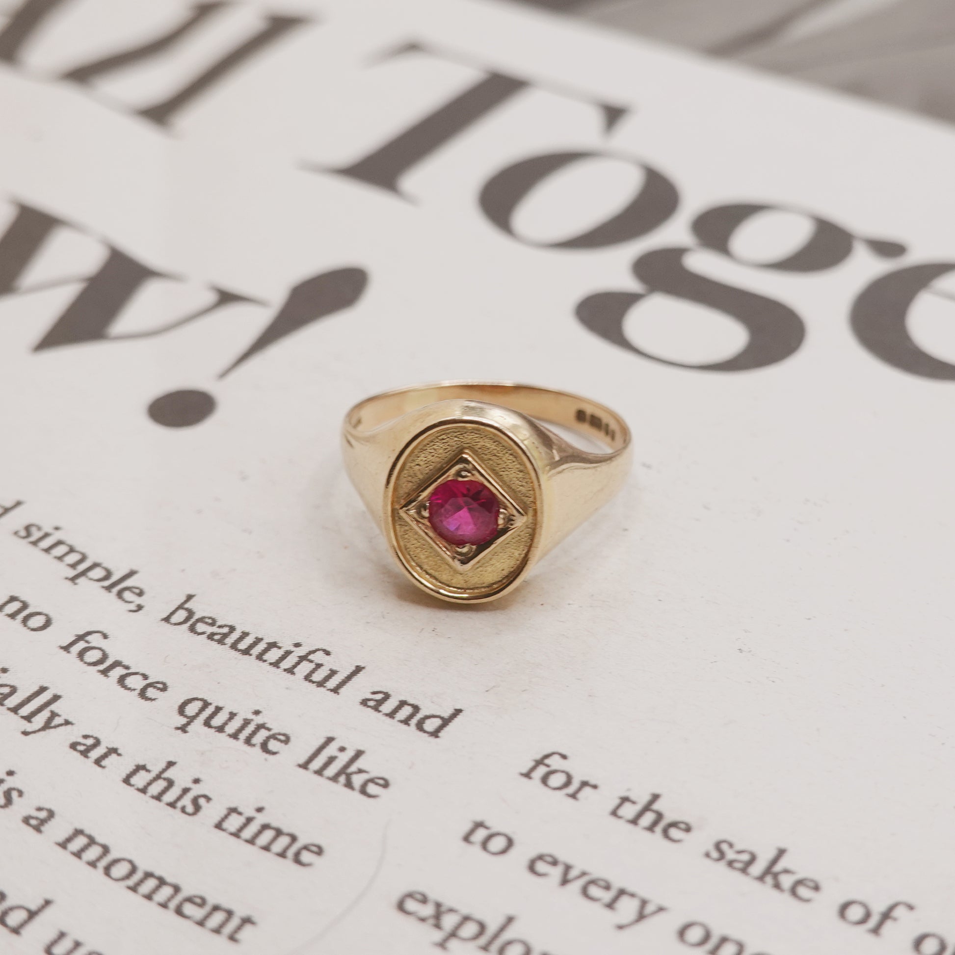 Gold ring with a red gemstone on a newspaper background