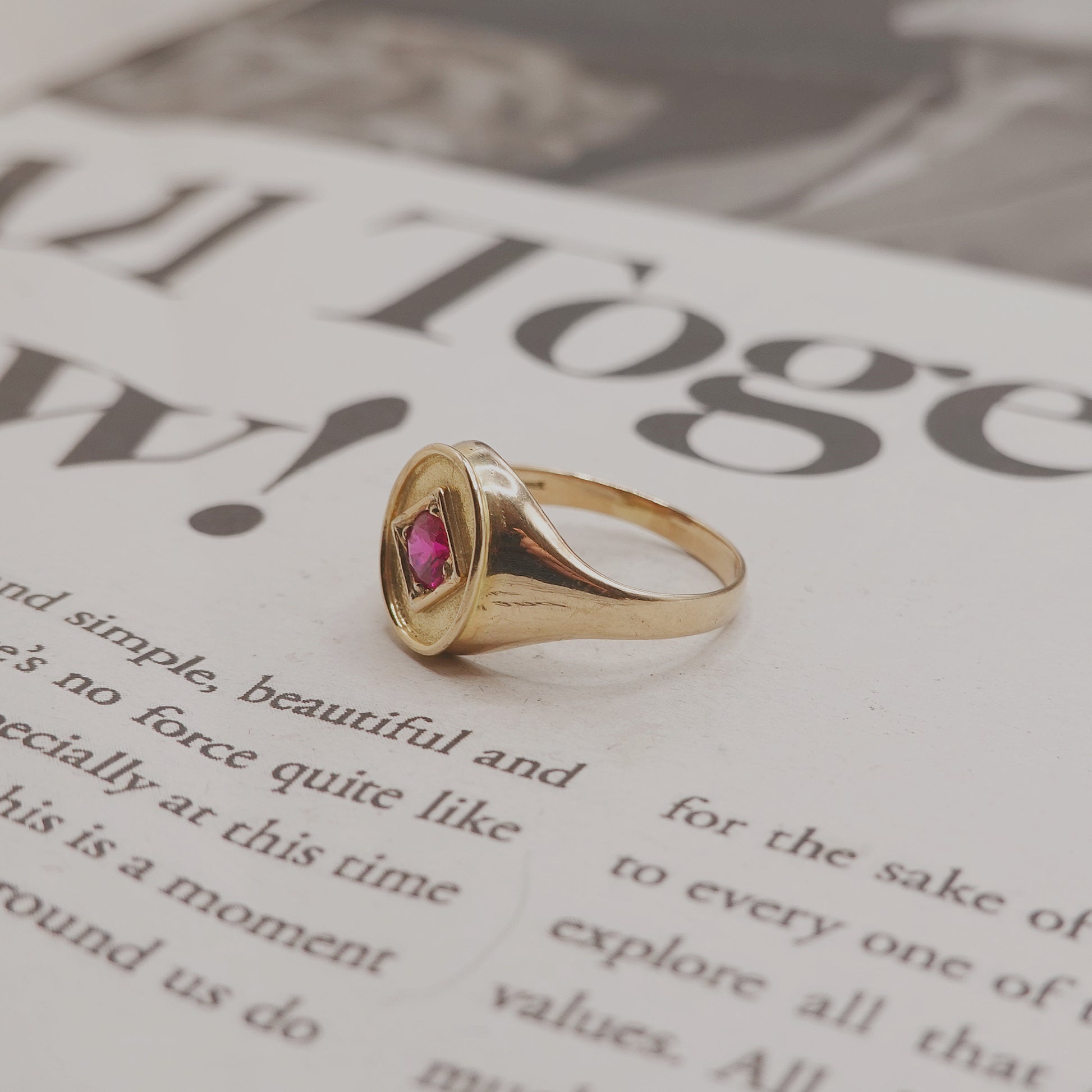 Gold ring with a pink gemstone on a magazine page