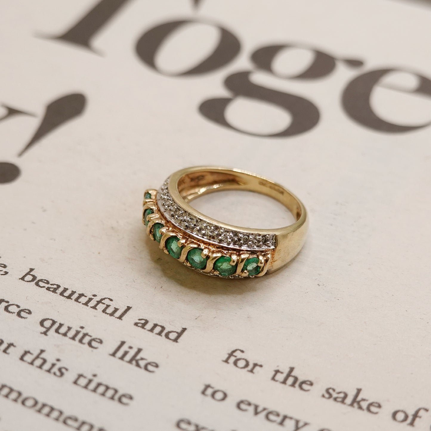 Gold ring with green emerald and diamonds on a magazine page