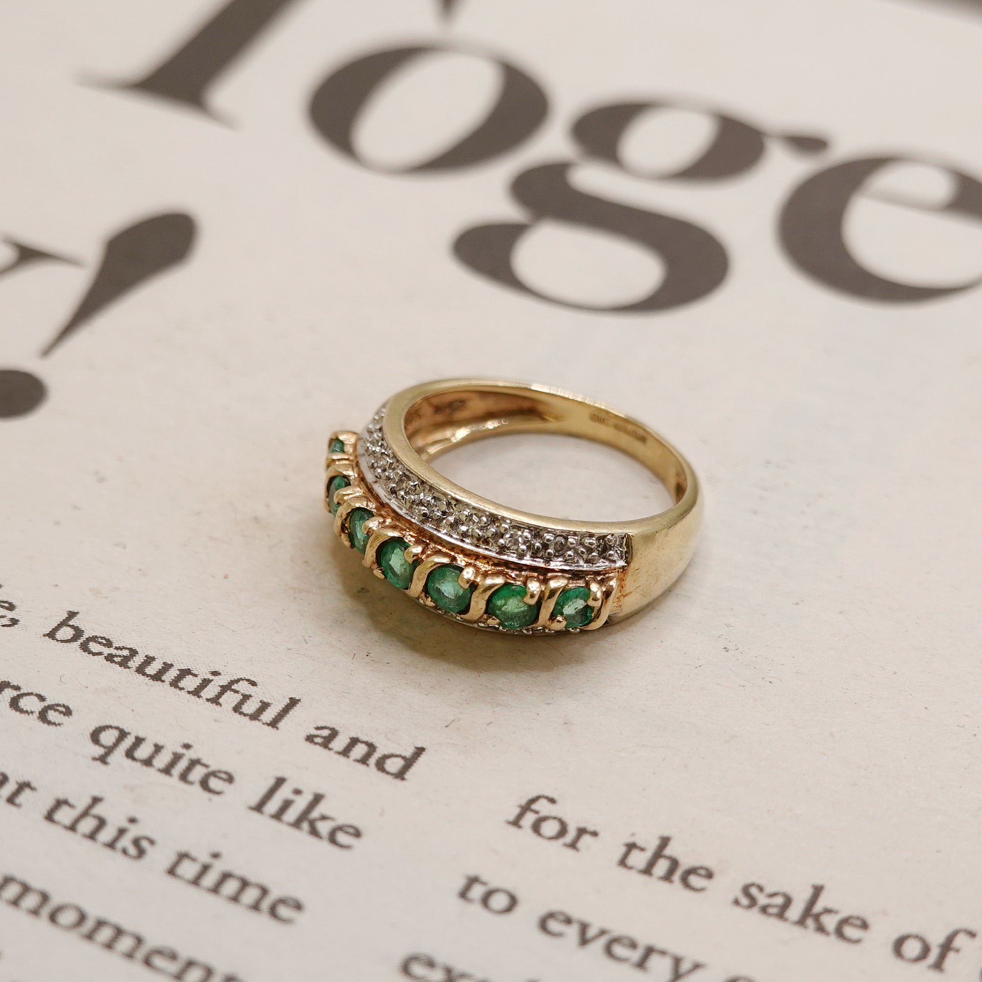 Gold ring with green emerald and diamonds on a magazine page